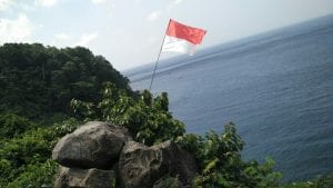 indonesian flag flying on a coast side near the water