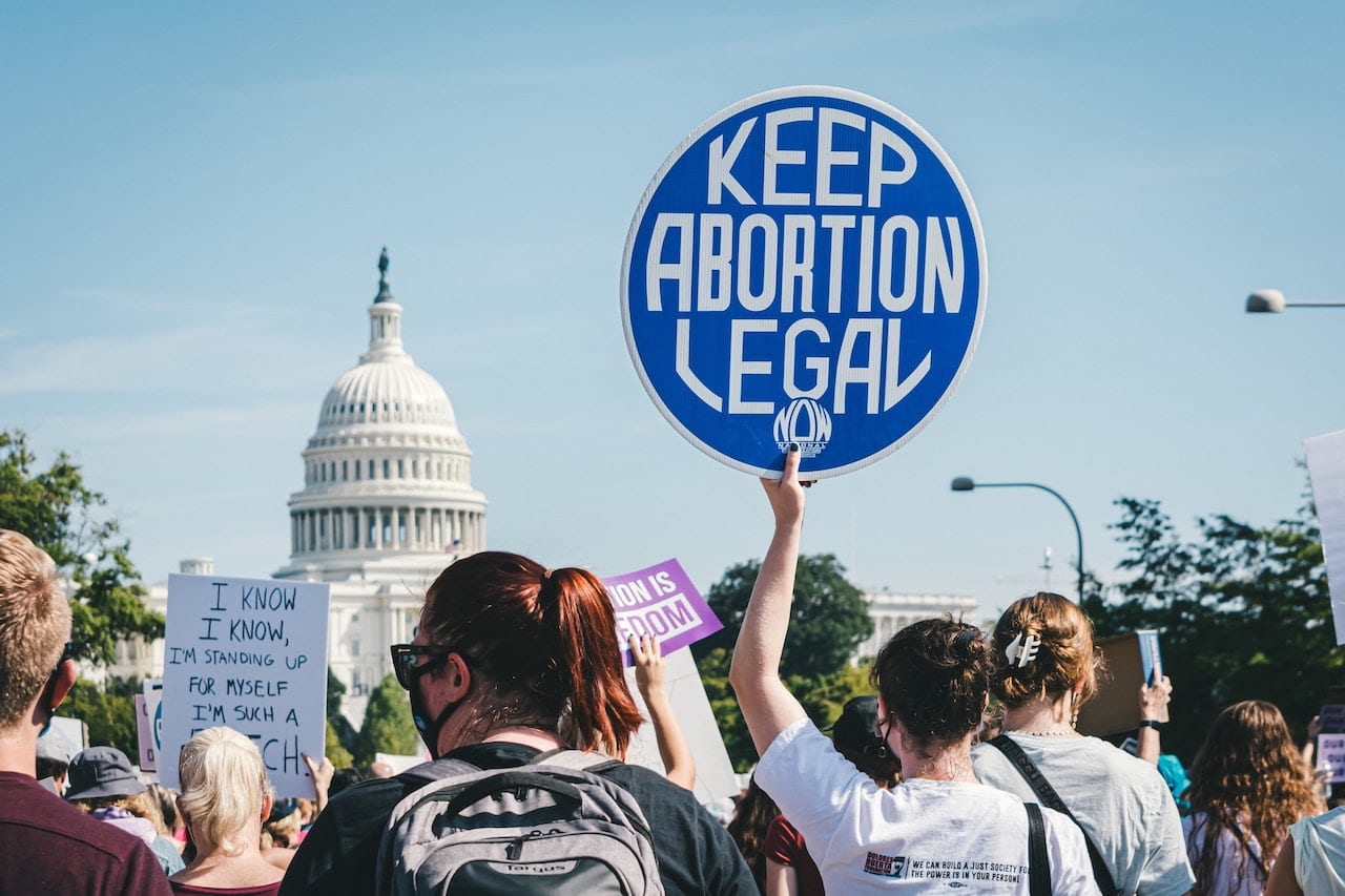 Photograph of a pro-choice march outside the U.S. Capitol. A march attendee's sign reads "keep abortion legal"