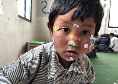 Little boy looks directly into the camera with stickers pasted all over his face