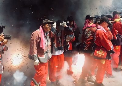 A group of men sand among the exploding fireworks in protective clothing.