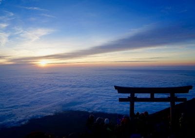 Silhouette of an archway as the sun sets over the clouds surrounding the summit