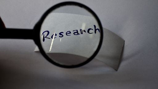 Image of a magnifying glass over a piece of paper with the word "Research" written on it.