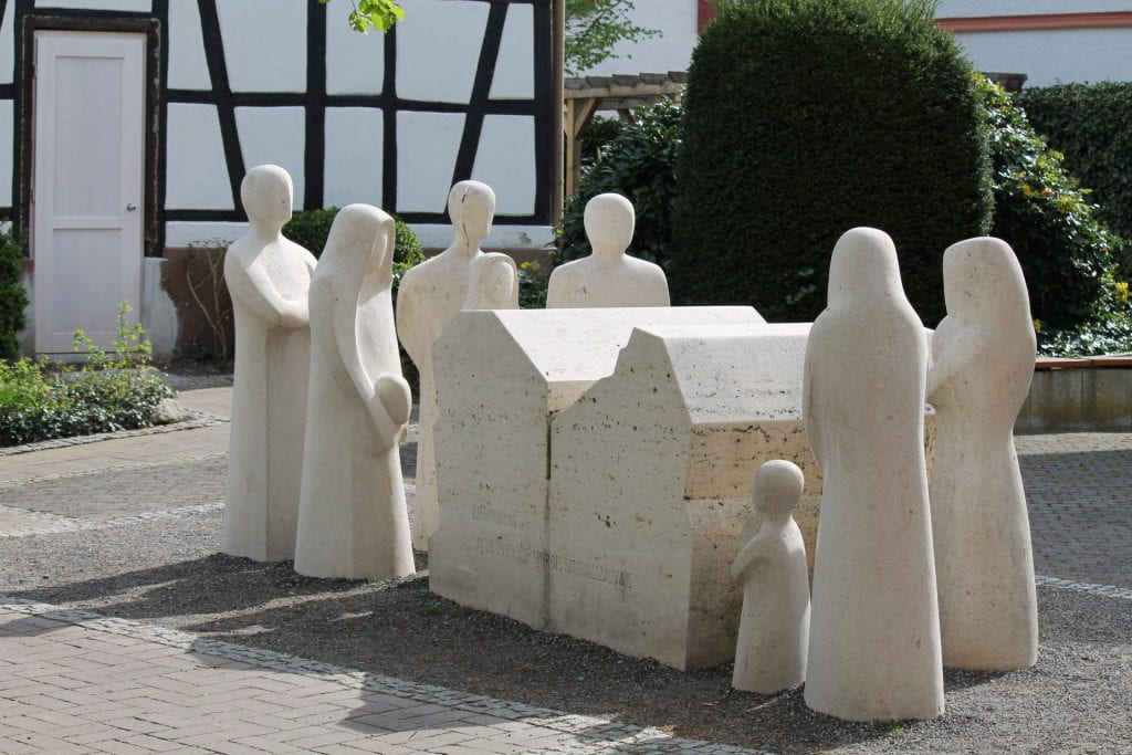 Image of stone Holocaust memorial sculpture (adults and children paying respects to victims).