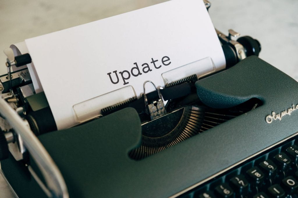 Photograph of a typewriter with a piece of paper with the word "Update" typed on it in large font.