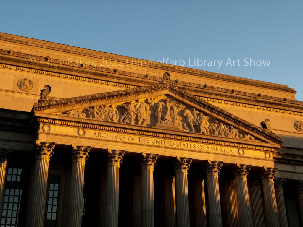 Photograph of the National Archives building in Washington DC with golden sunlight hitting the top third of the building and the bottom third of the image is in shadows.