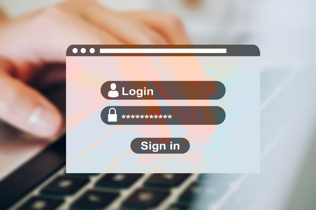 Image of a login screen with a hand on a keyboard in the background.