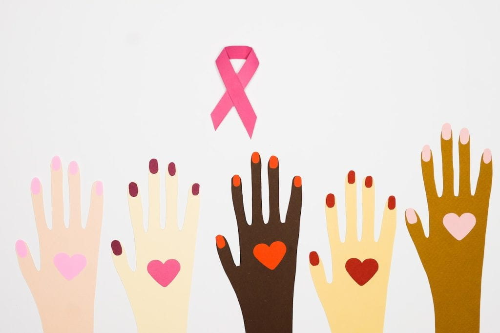 Image of pink ribbon and hands of varying skin tones with hearts.
