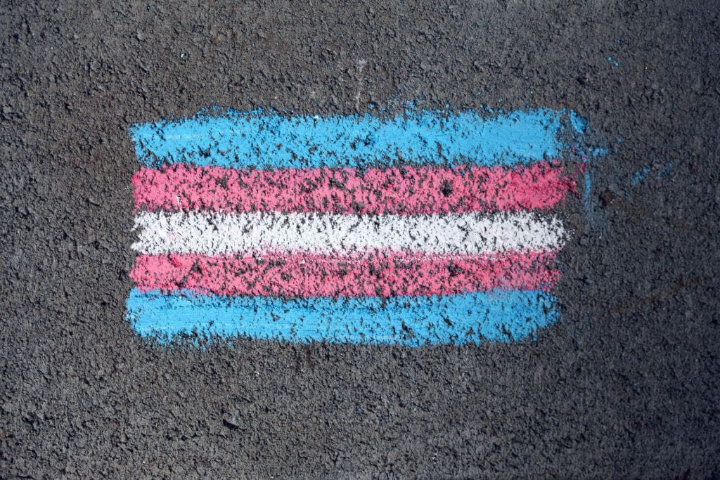 The Transgender pride flag done in chalk on a gravel background
