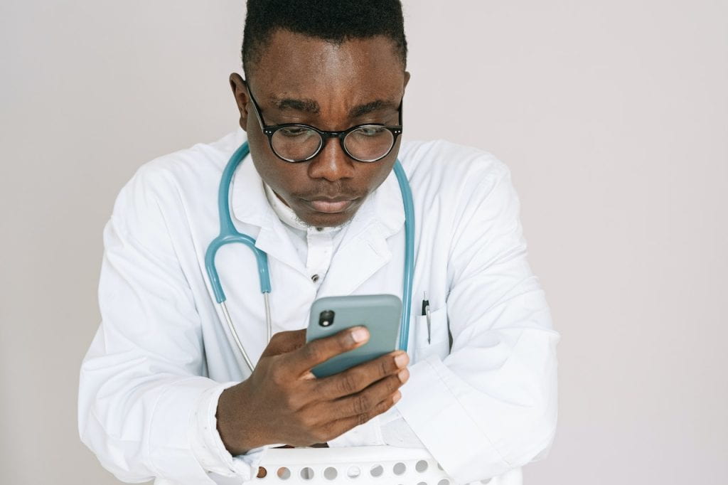 Healthcare professional with stethoscope holding smart phone image by Ivan Samkov on Pexels
