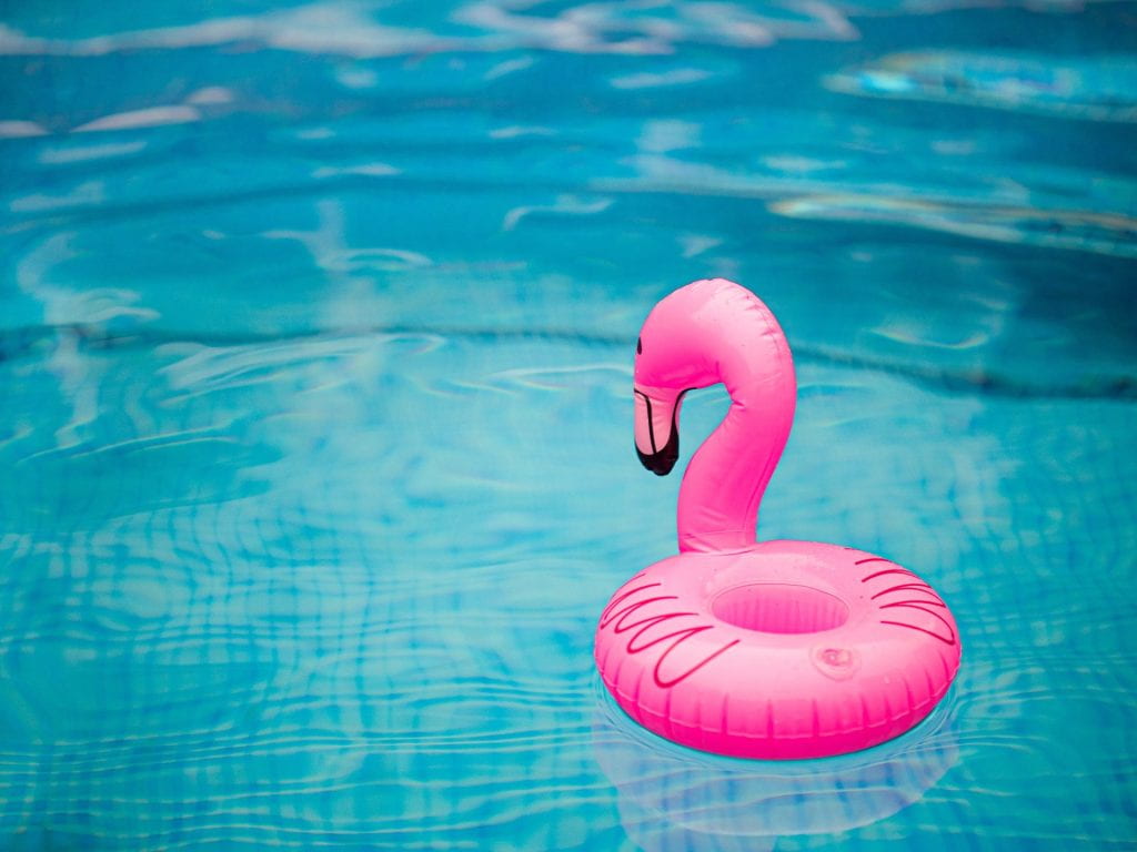 Picture of an inflatable pink flamingo raft floating in a pool.