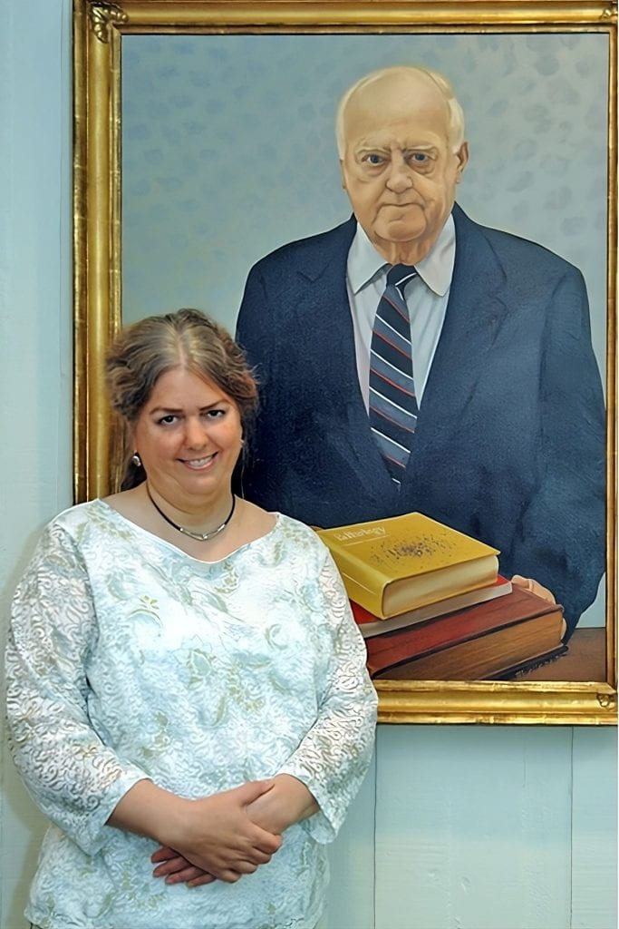 Catherine standing next to the portrait of her father, Frank Miller.