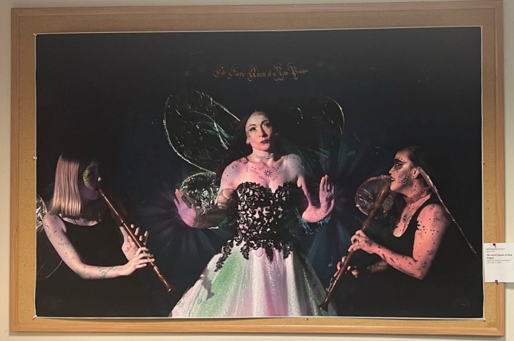 Painting of a Faerie Queen with two women playing woodwind instruments looking at her.