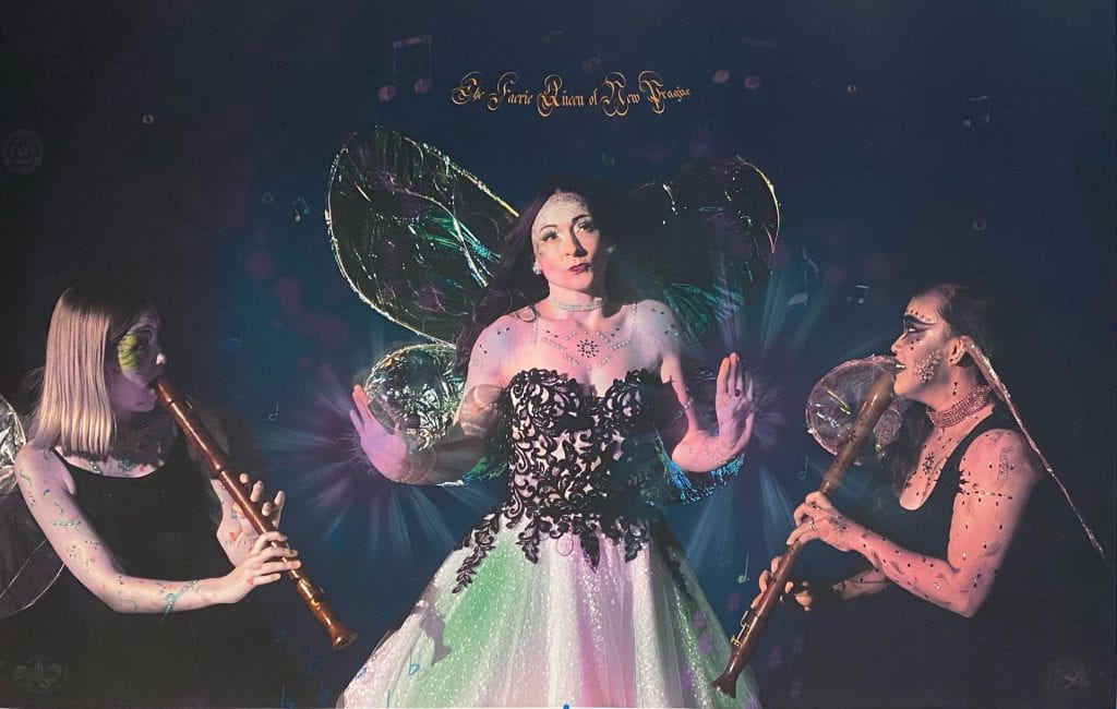 Image of Faerie Queen with two women playing wooden instruments on either side.