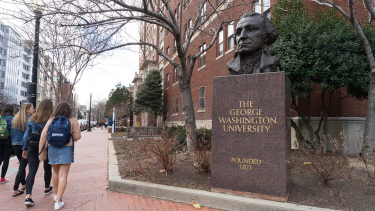 Students walking past bust of George Washington and sign for GW University