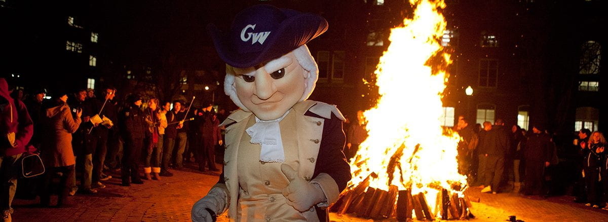 GW George mascot in front of a bonfire